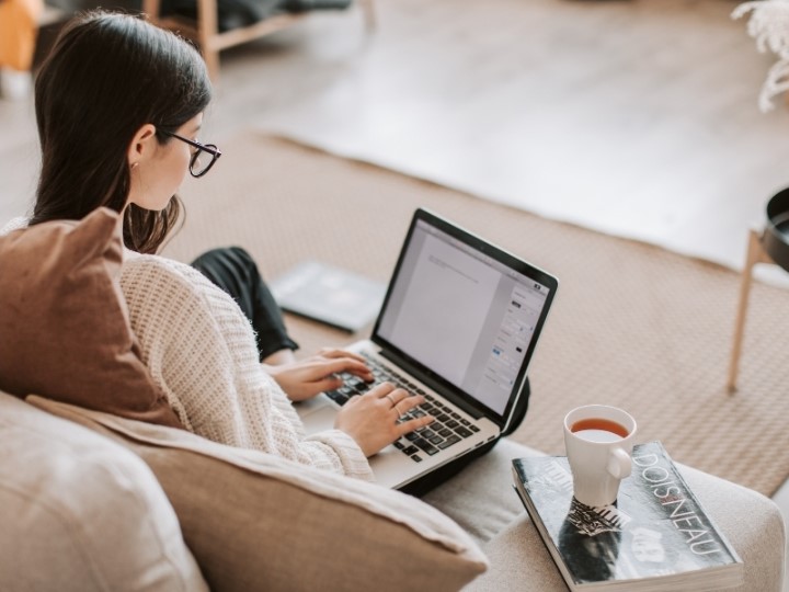 Eine Frau sitzt mit Laptop auf der Couch